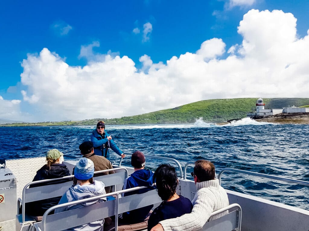 Tour boat of passengers passing by Valentia Lighthouse on a sunny day