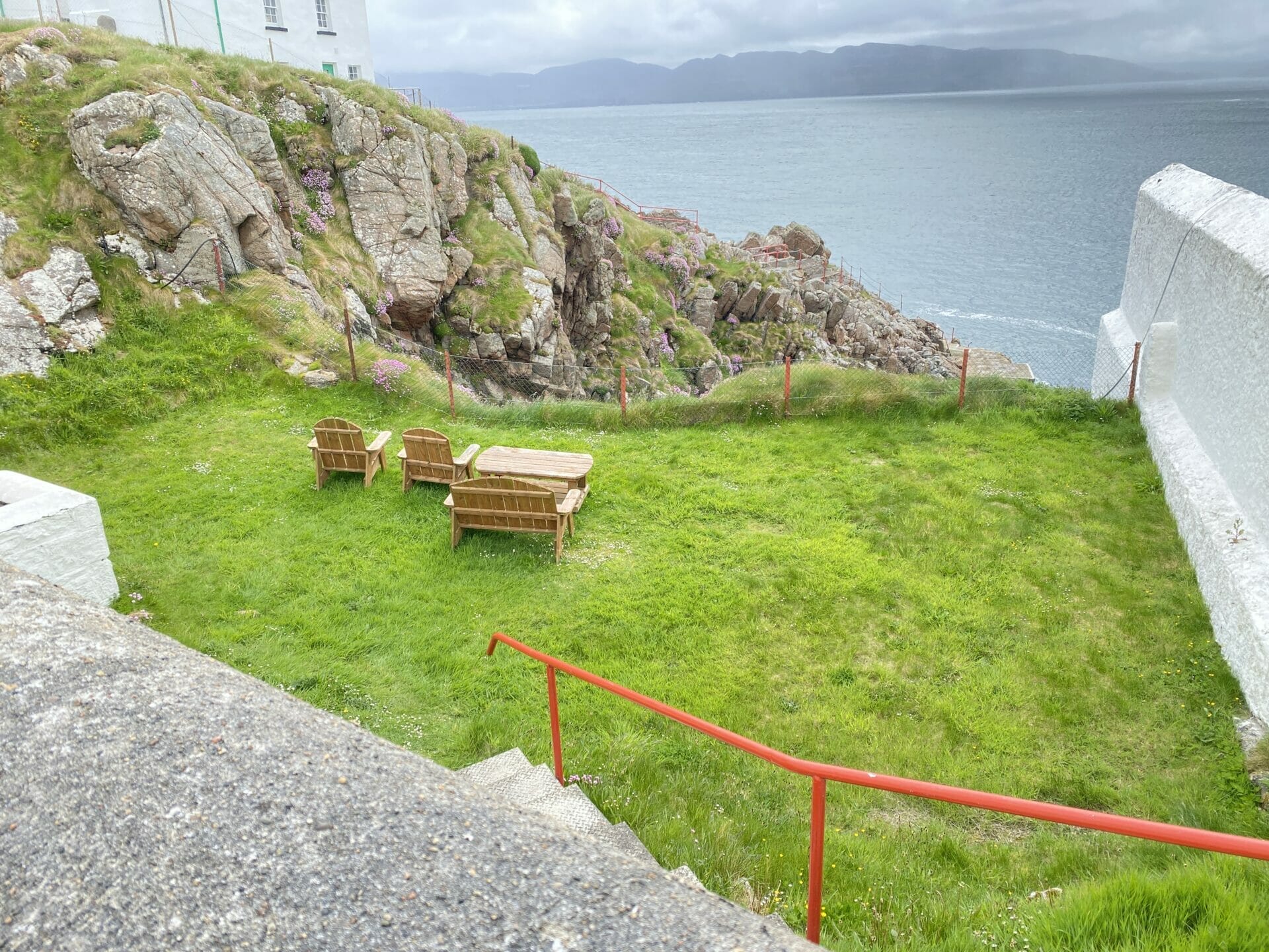 Patch of grass by Fanad lighthouse with sea in the background and picnic benches in foreground