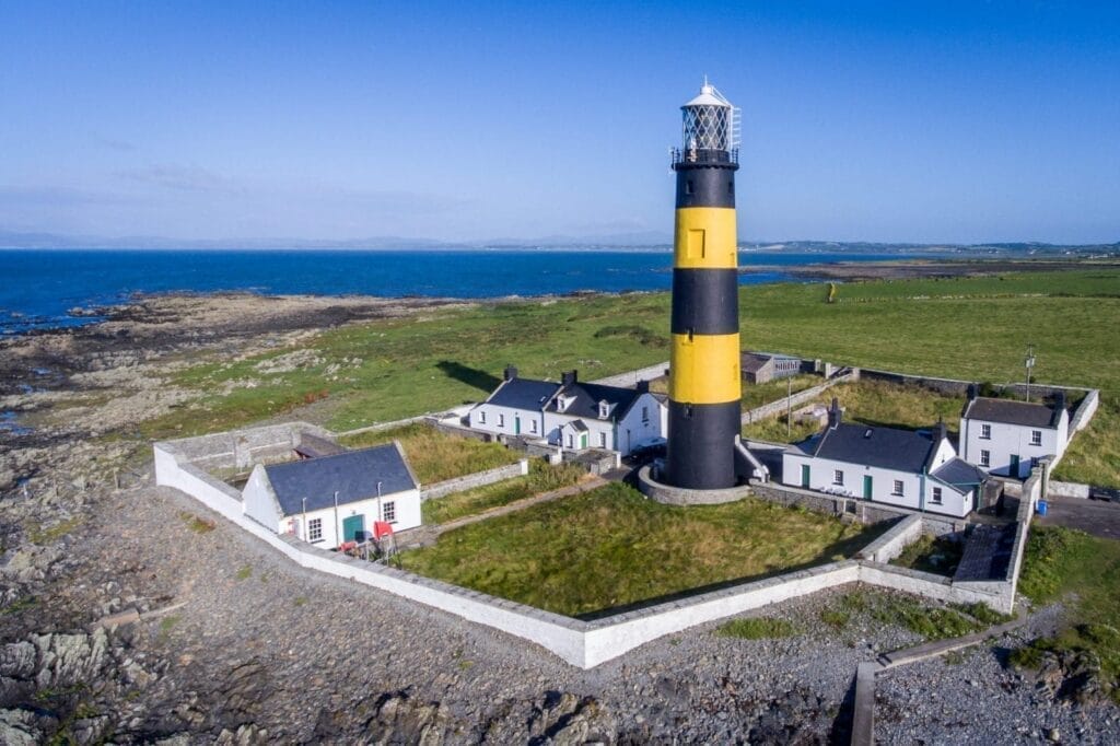 A black and yellow striped lighthouse on the coast